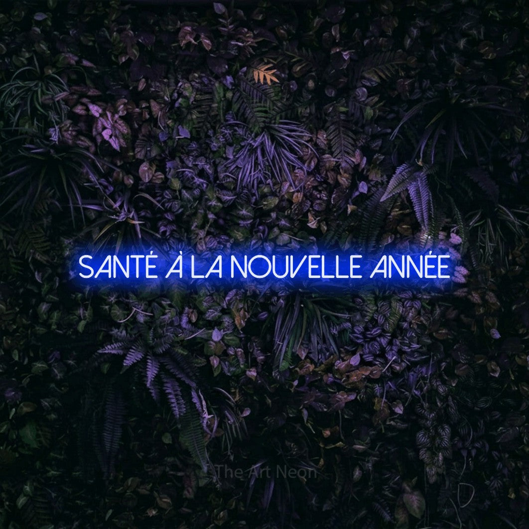 “Santé à la nouvelle année” LED neon sign in blue, with thin sans-serif lettering, shown against a dark wall with purple flowers.