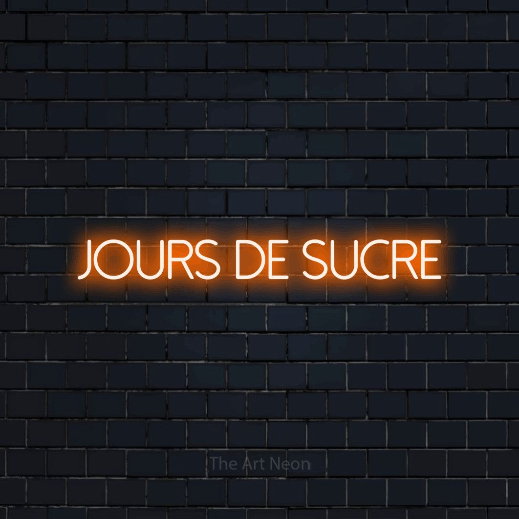 “Jours de sucre” LED neon sign in orange, with thin sans-serif lettering, shown against a dark navy brick wall.