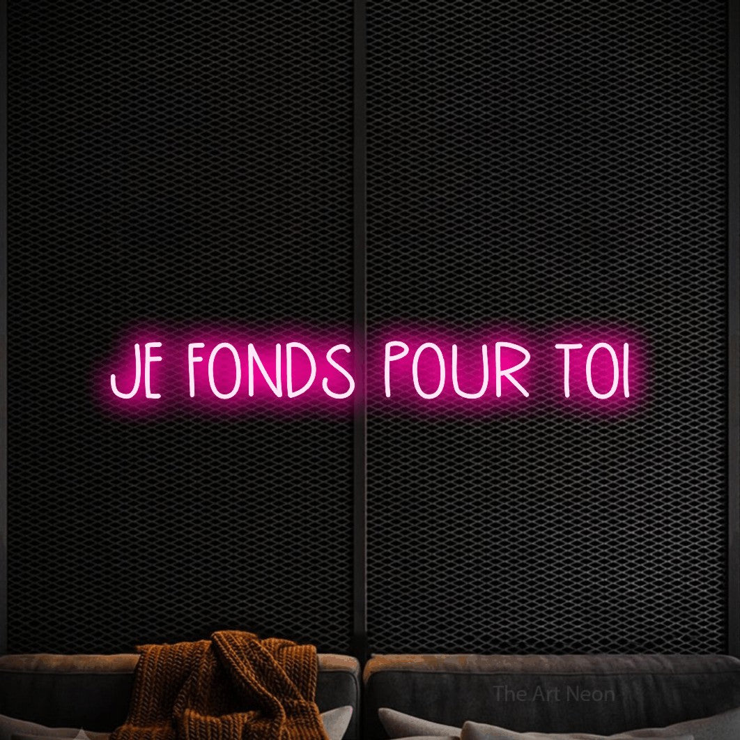 “Je fonds pour toi” LED neon sign in hot pink, with narrow hand-drawn lettering, shown against a modern dark-toned seating area.