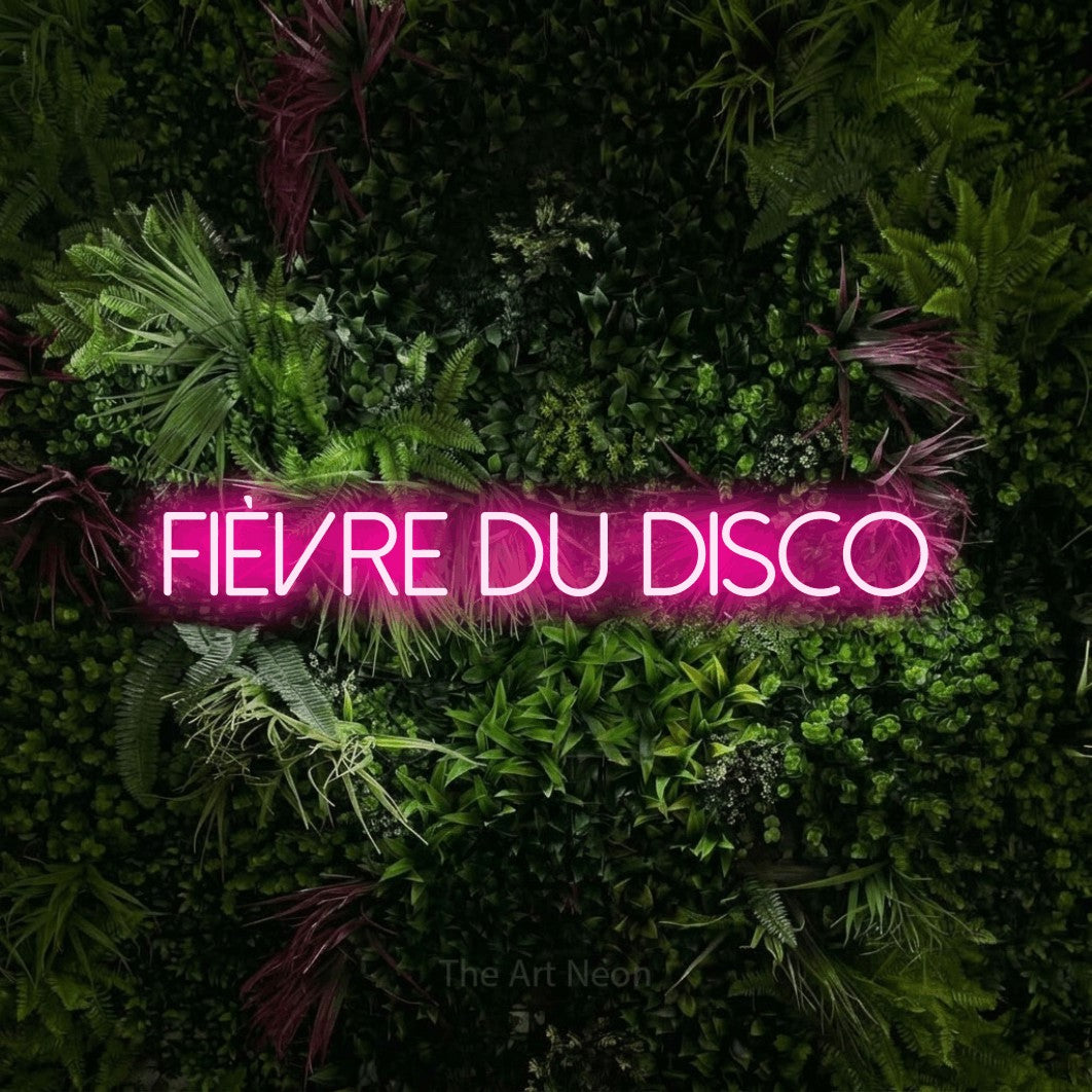 Aperçu d’une enseigne néon LED « Fièvre du disco » en rose vif, en lettres fines sans empattement, photographiée sur un mur végétal aux fleurs roses, pour une fête.