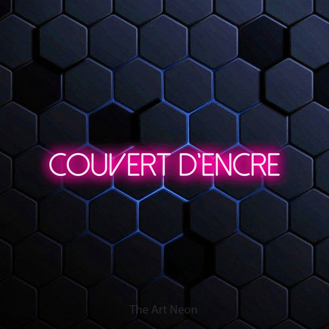 “Couvert d'encre” LED neon sign in hot pink, with thin sans-serif lettering, shown against a dark blue honeycomb pattern.
