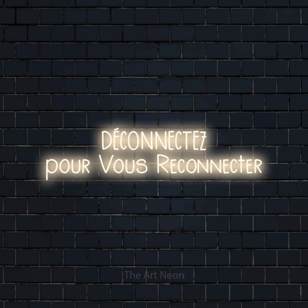 “Déconnectez pour vous reconnecter” LED neon sign in warm white, with narrow hand-drawn lettering across 2 lines, shown against a dark navy brick wall.