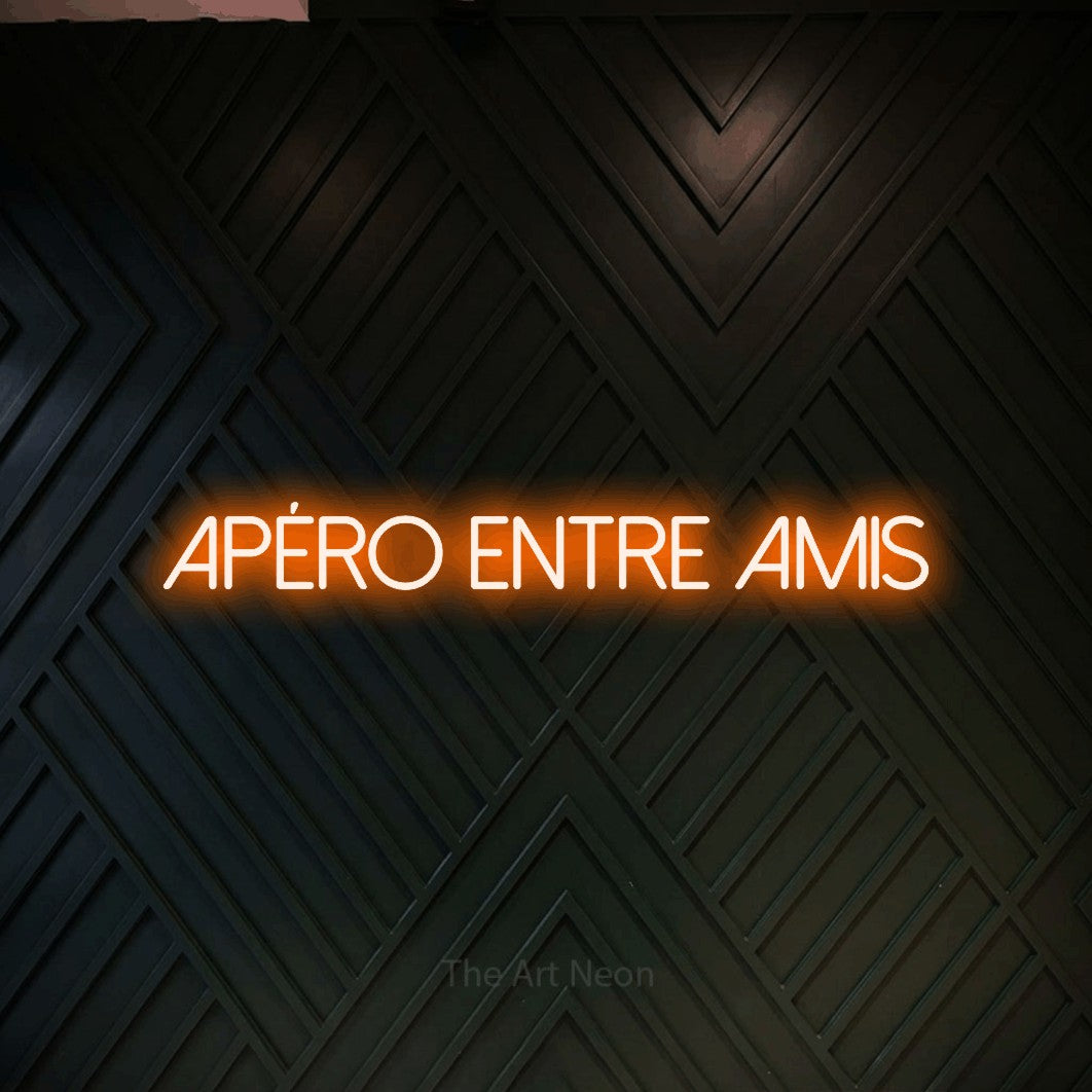 “Apéro entre amis” LED neon sign in orange, with thin sans-serif lettering, shown against a black chevron-patterned wood wall.