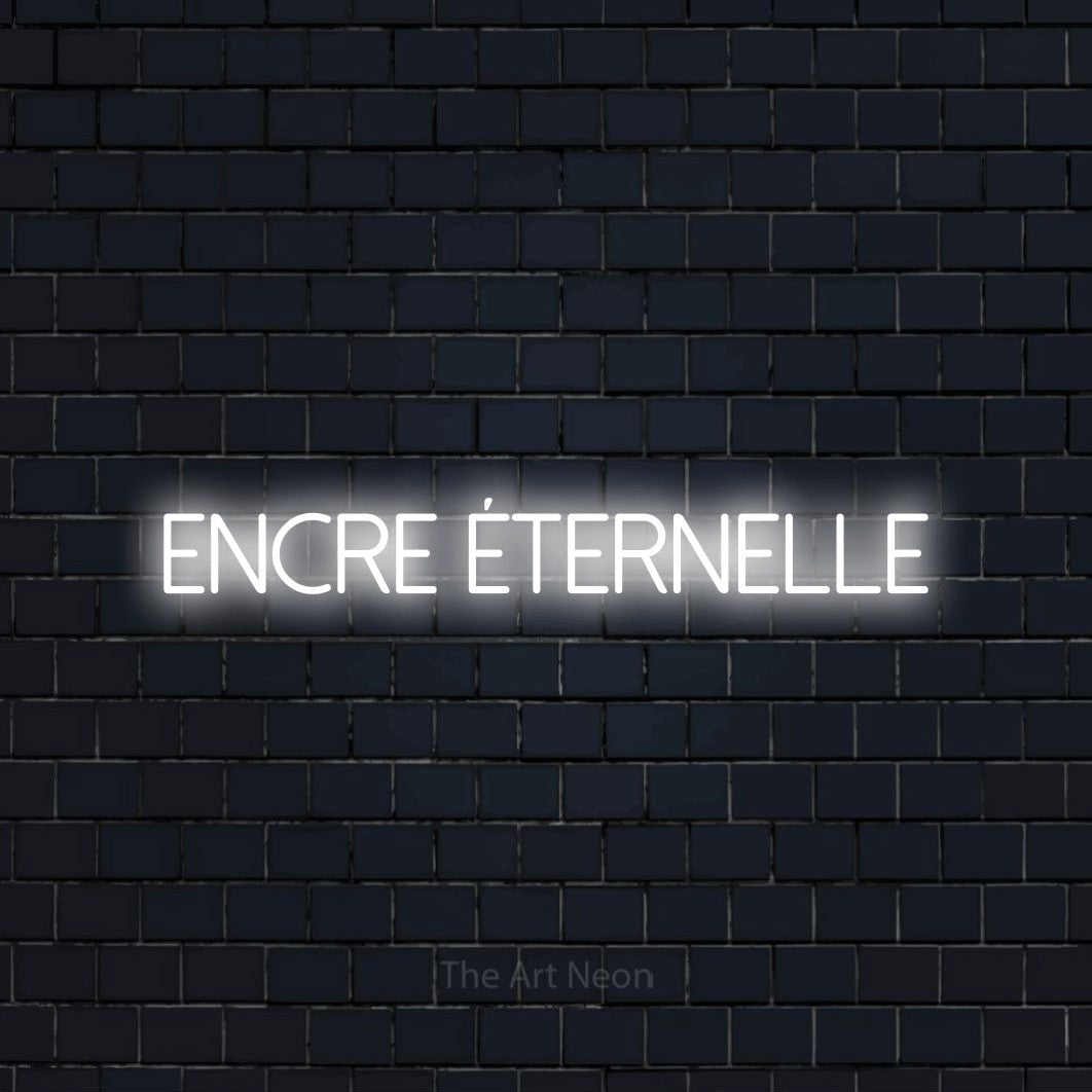 “Encre éternelle” LED neon sign in cool white, with thin sans-serif lettering, shown against a dark navy brick wall.