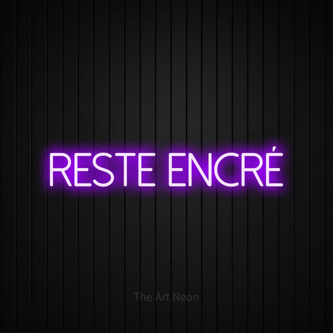 “Reste encré” LED neon sign in purple, with thin sans-serif lettering, shown against black vertical wall slats.