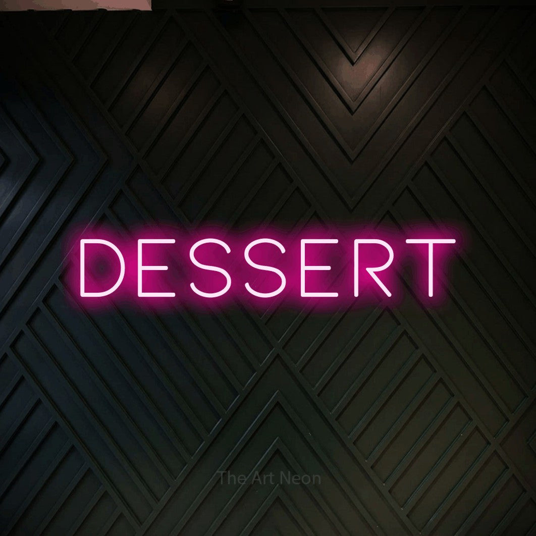 “Dessert” LED neon sign in hot pink, with thin, widely spaced lettering, shown against a black chevron-patterned wood wall.