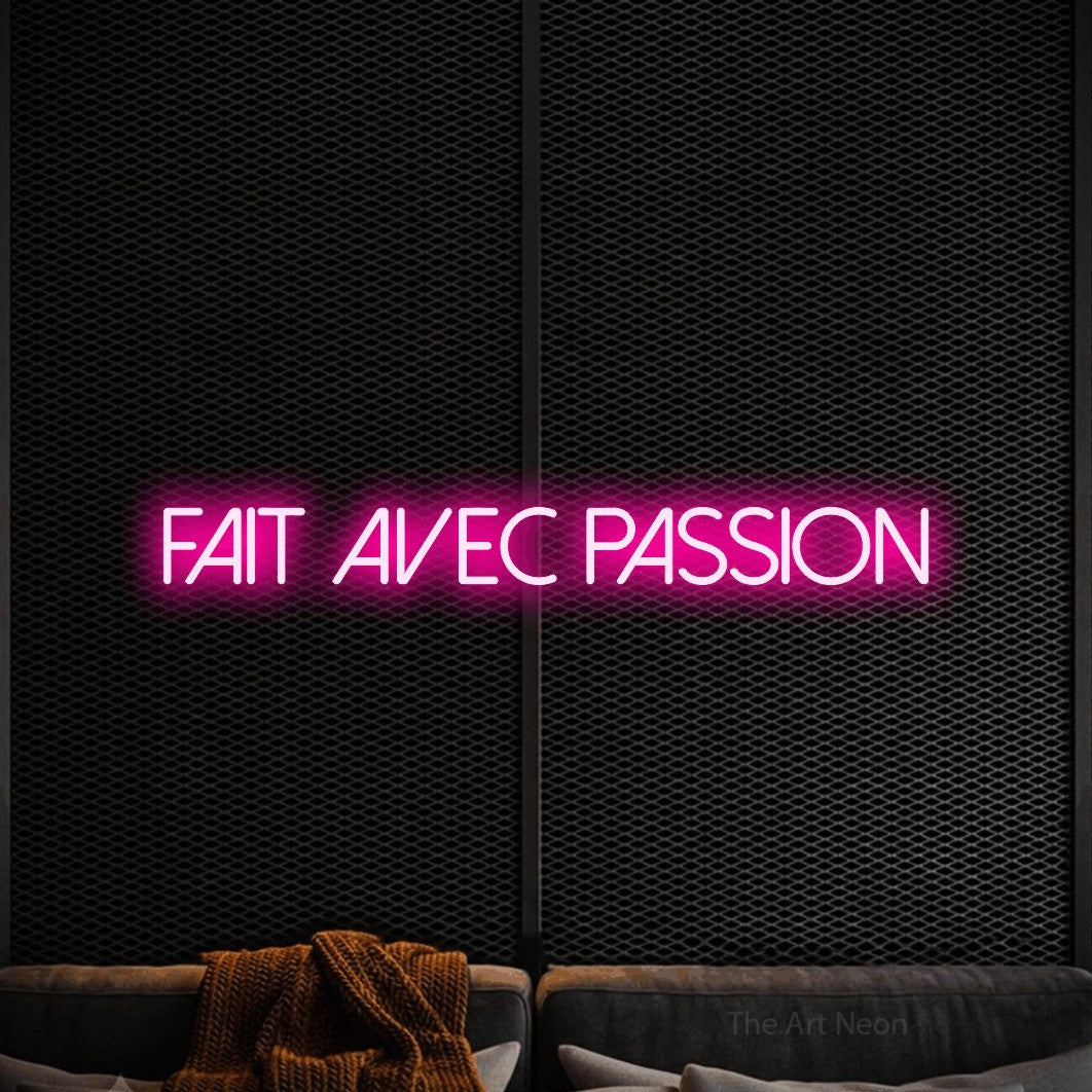 “Fait avec passion” LED neon sign in hot pink, with thin sans-serif lettering, shown against a modern dark-toned seating area.