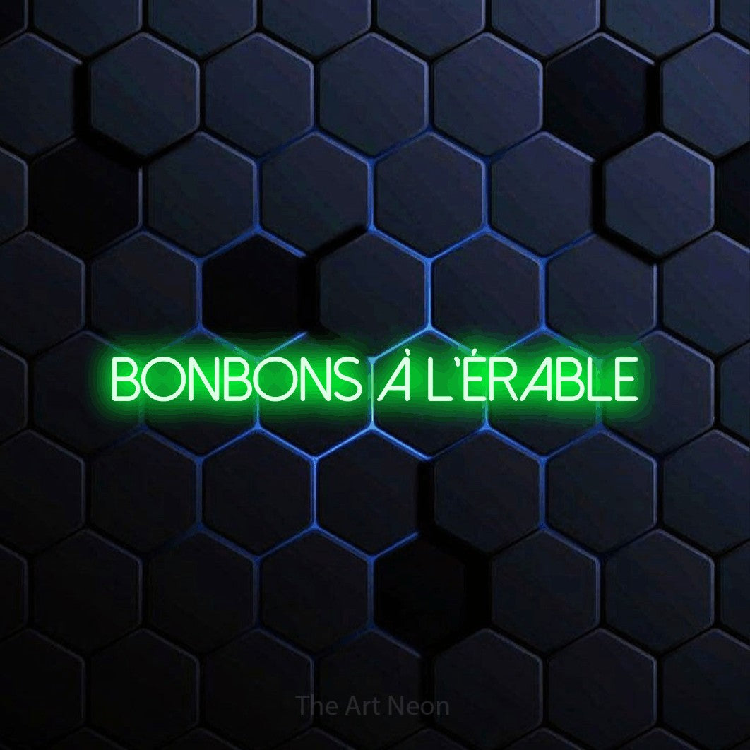 “Bonbons à l'érable” LED neon sign in green, with thin sans-serif lettering, shown against a dark blue honeycomb pattern.