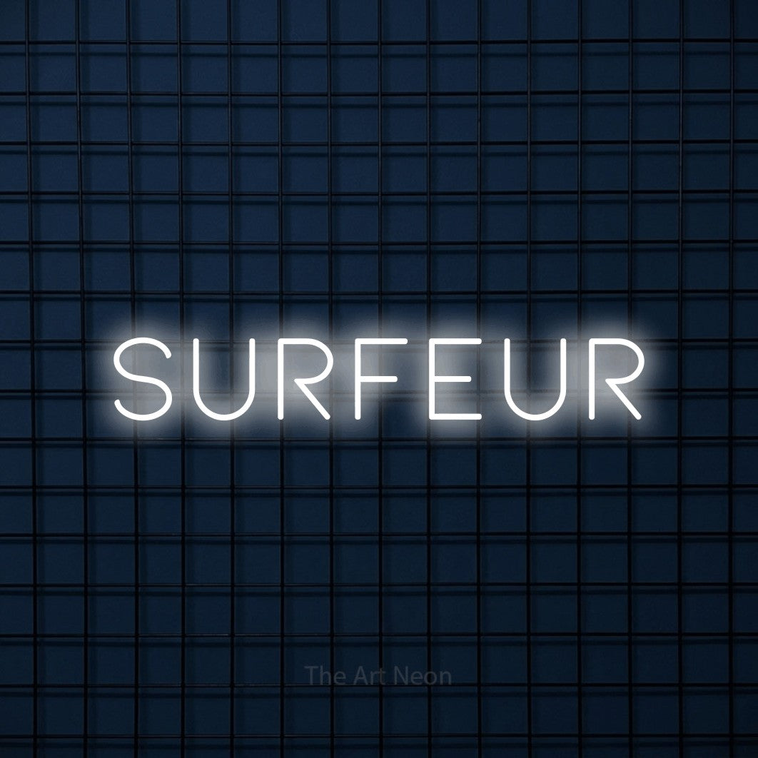 “Surfeur” LED neon sign in cool white, with thin, widely spaced lettering, shown against a dark blue grid.