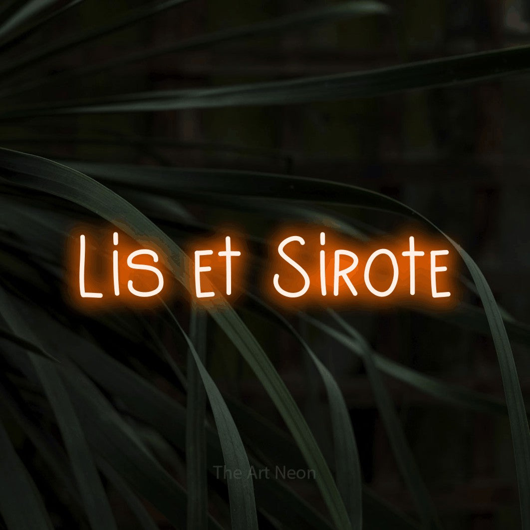 “Lis et sirote” LED neon sign in orange, with narrow hand-drawn lettering, shown against a close-up of dark foliage.