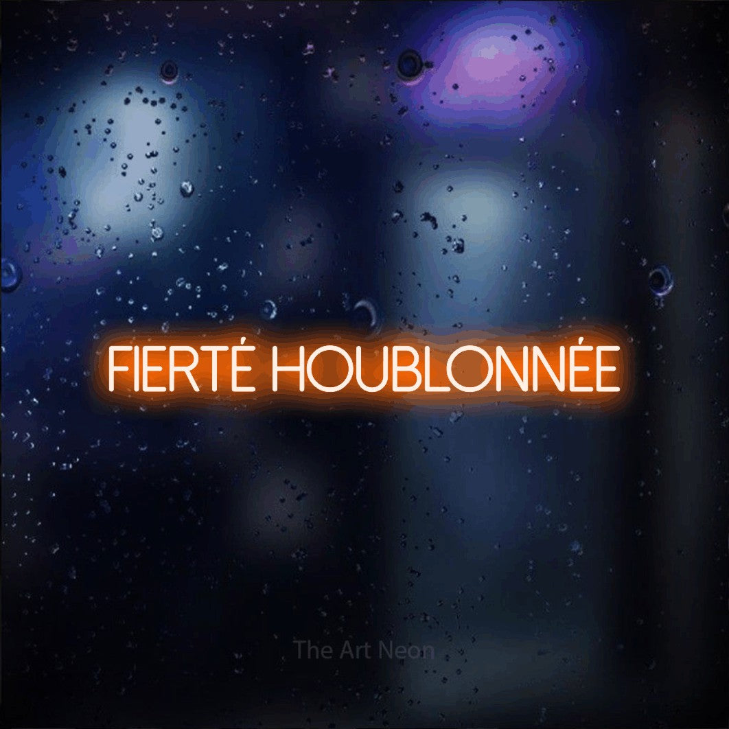 “Fierté houblonnée” LED neon sign in orange, with thin sans-serif lettering, shown against glass with blue and purple reflections.