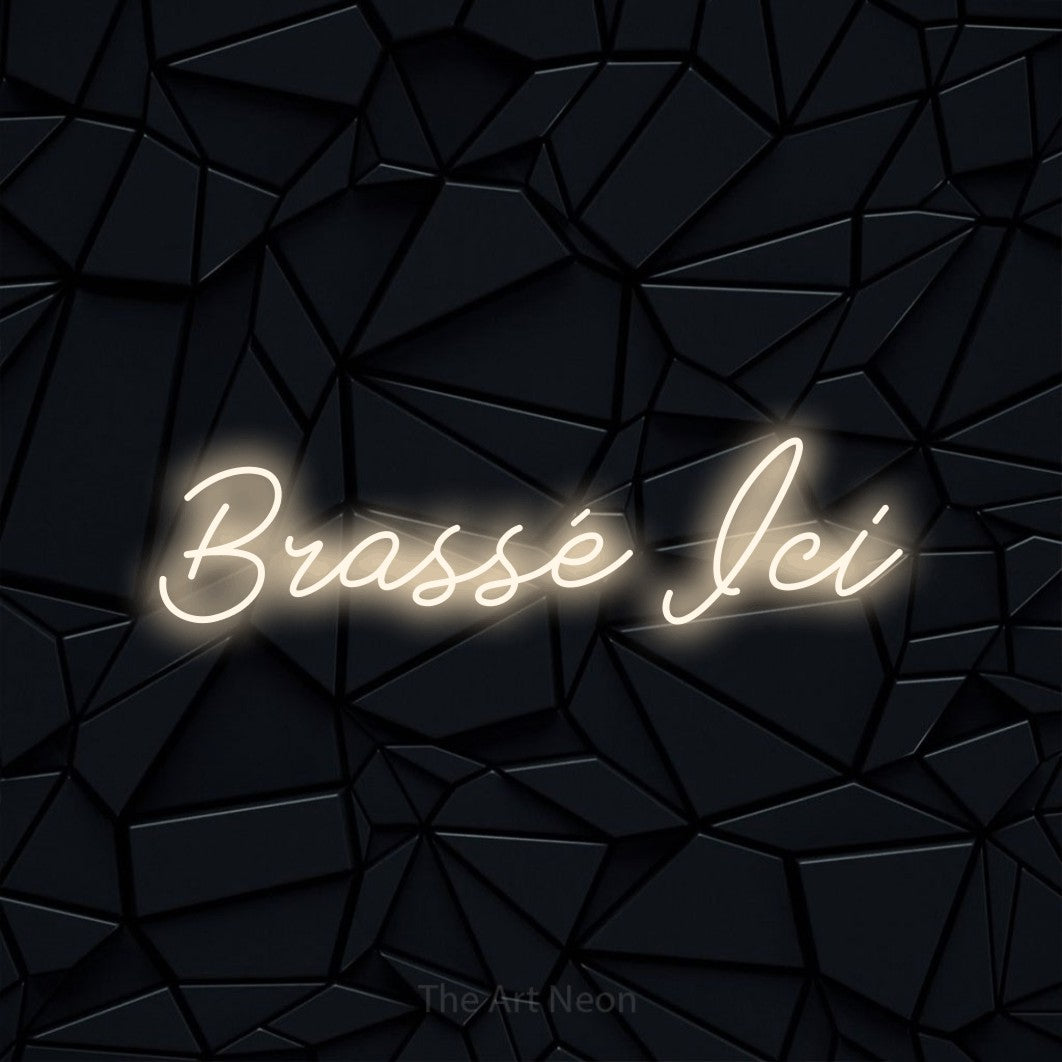 “Brassé ici” LED neon sign in warm white, with cursive lettering, shown against a black polygonal surface.