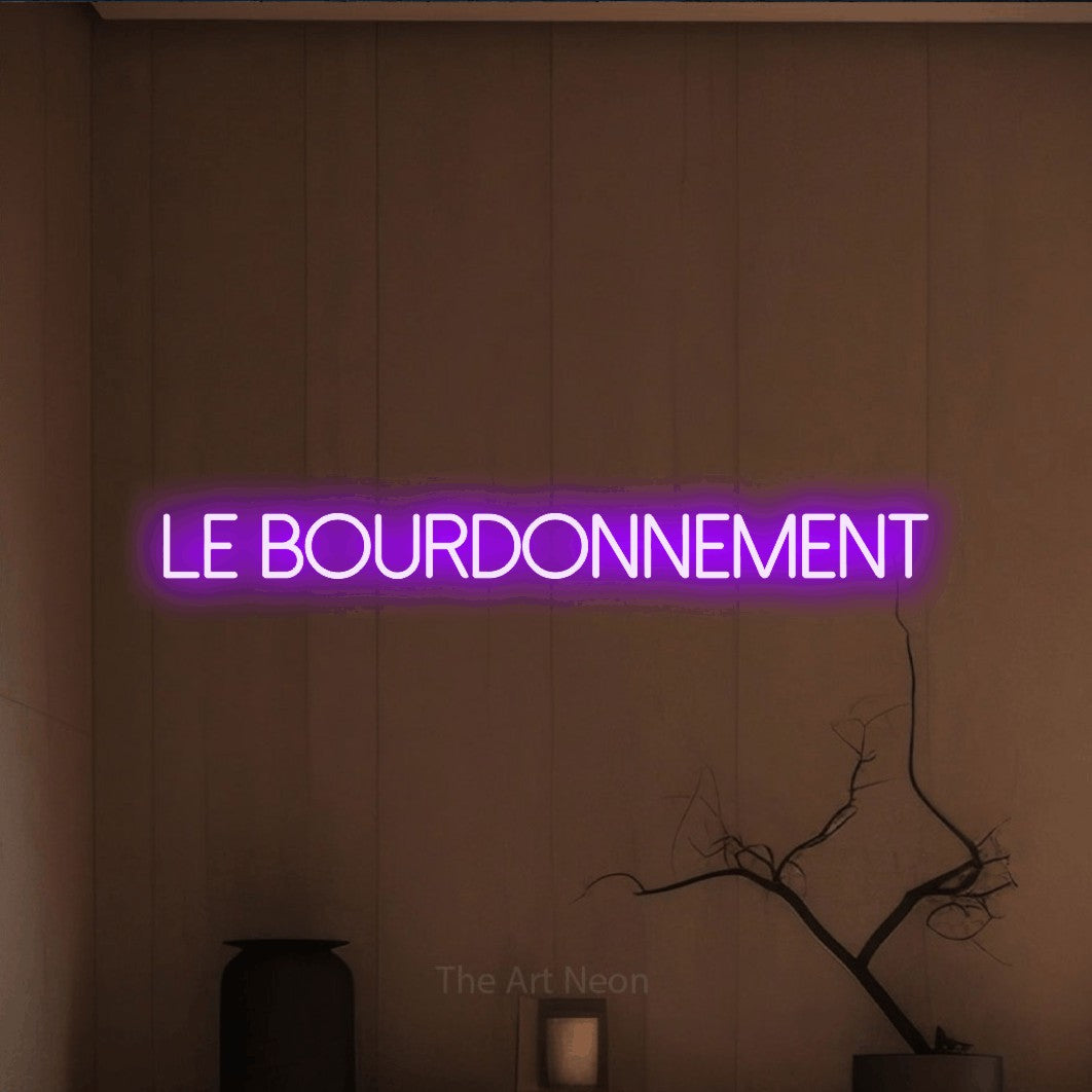 “Le bourdonnement” LED neon sign in purple, with thin sans-serif lettering, shown against a simple earth-toned interior.