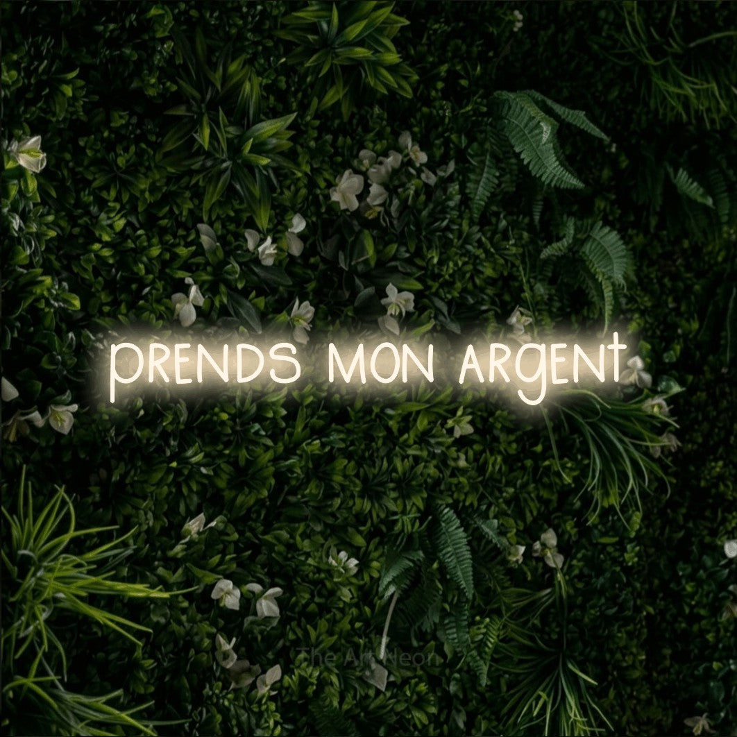 “Prends mon argent” LED neon sign in warm white, with narrow hand-drawn lettering, shown against a dense green plant wall.
