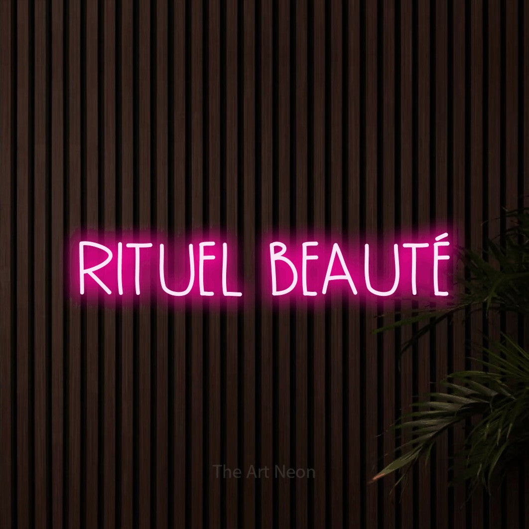 “Rituel beauté” LED neon sign in hot pink, with narrow hand-drawn lettering, shown against dark wooden wall slats.