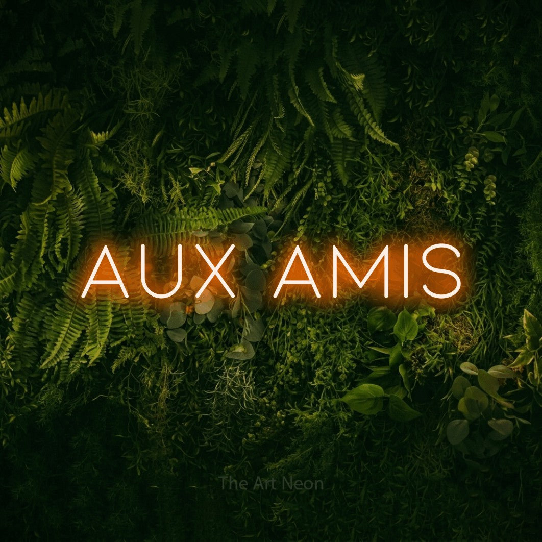 “Aux amis” LED neon sign in orange, with thin, widely spaced lettering, shown against a dark moss and forest backdrop.