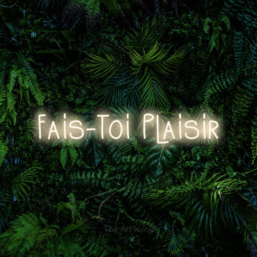 “Fais-toi plaisir” LED neon sign in warm white, with narrow hand-drawn lettering, shown against dense tropical foliage.
