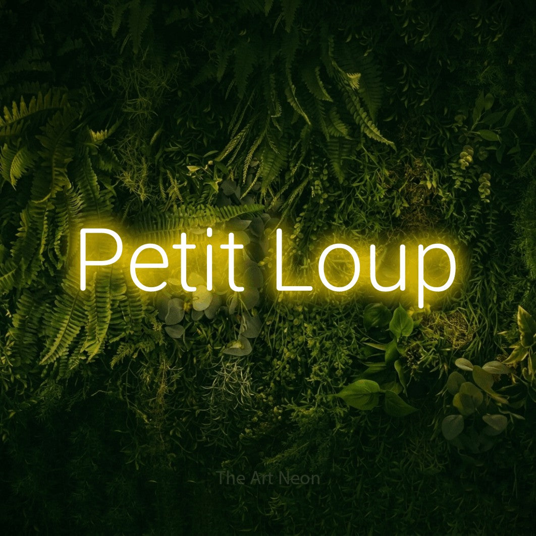 “Petit loup” LED neon sign in yellow, with rounded sans-serif lettering, shown against a dark moss and forest backdrop.