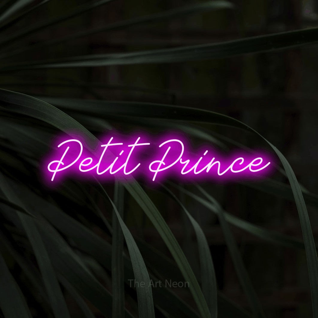 Composition en néon LED « Petit prince » en rose, en lettrage cursif, mise en valeur sur un feuillage sombre en gros plan, pour une chambre d’enfant.