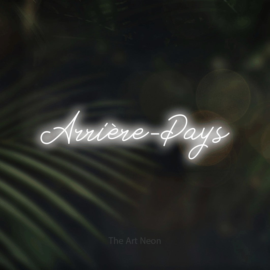 “Arrière-pays” LED neon sign in cool white, with cursive lettering, shown against a blurred palm and bokeh-light backdrop.