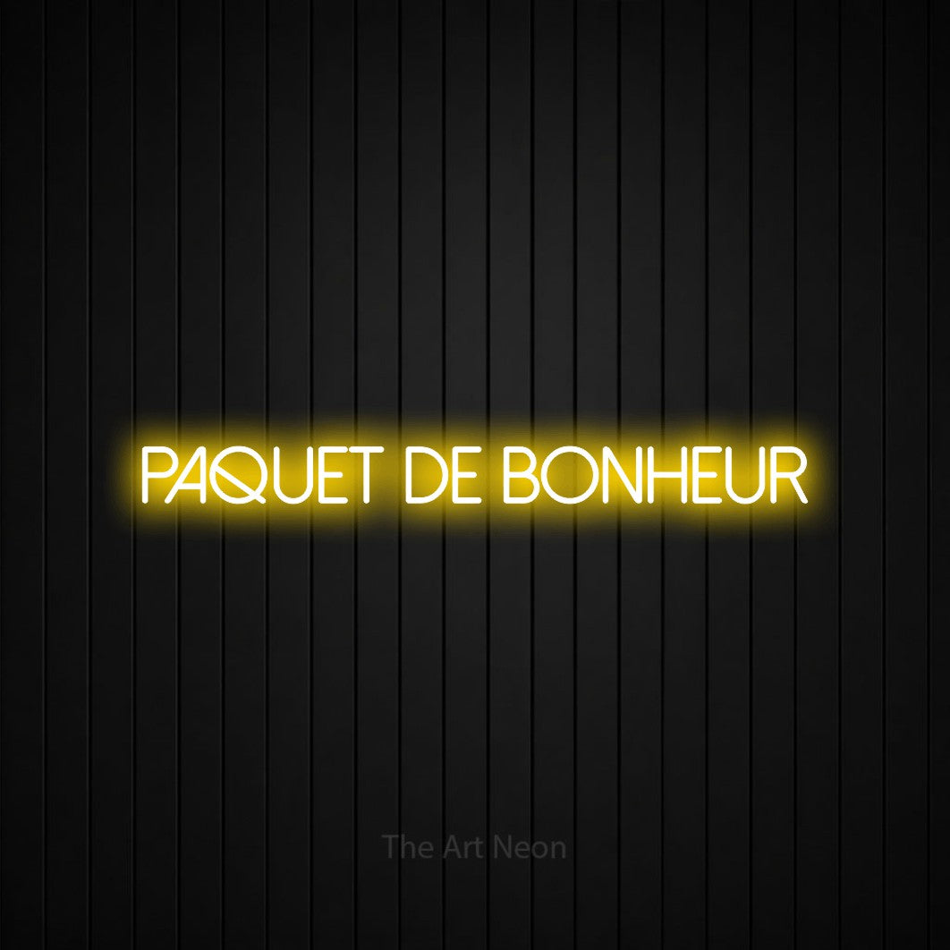 “Paquet de bonheur” LED neon sign in yellow, with thin sans-serif lettering, shown against black vertical wall slats.