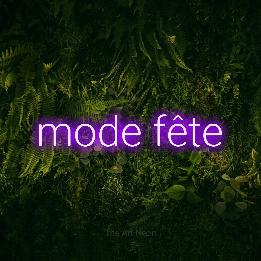 “Mode fête” LED neon sign in purple, with rounded sans-serif lettering, shown against a dark moss and forest backdrop.