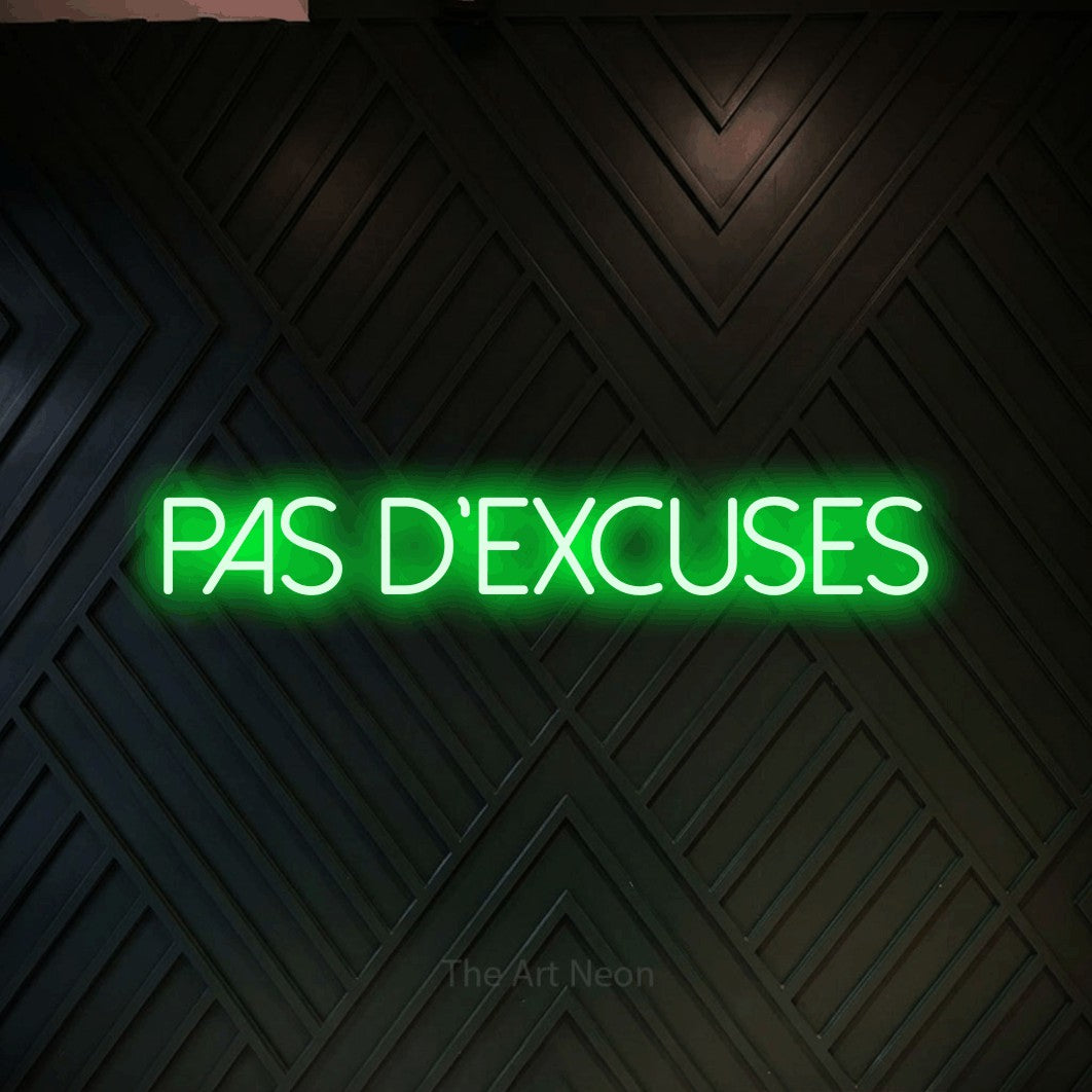 “Pas d'excuses” LED neon sign in green, with thin sans-serif lettering, shown against a black chevron-patterned wood wall.