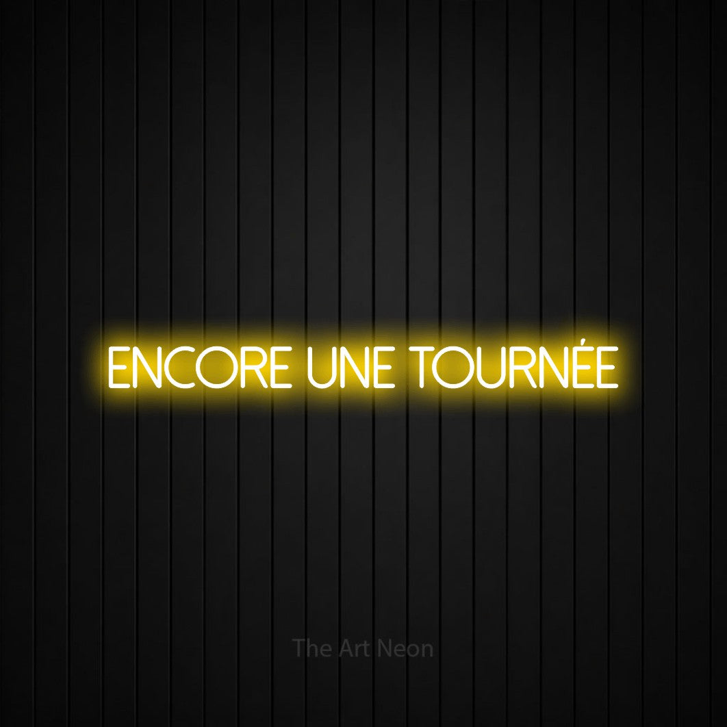 “Encore une tournée” LED neon sign in yellow, with thin sans-serif lettering, shown against black vertical wall slats.