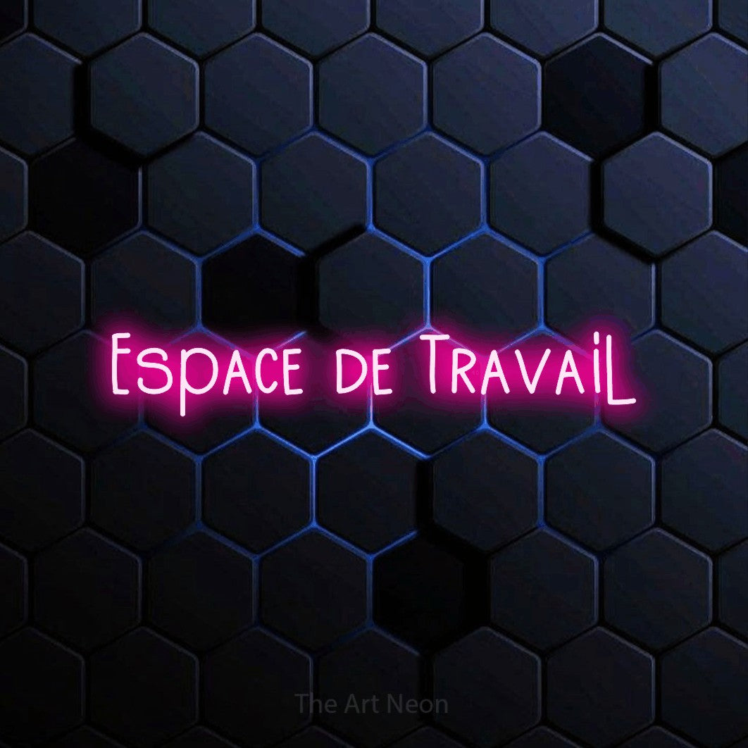 “Espace de travail” LED neon sign in hot pink, with narrow hand-drawn lettering, shown against a dark blue honeycomb pattern.