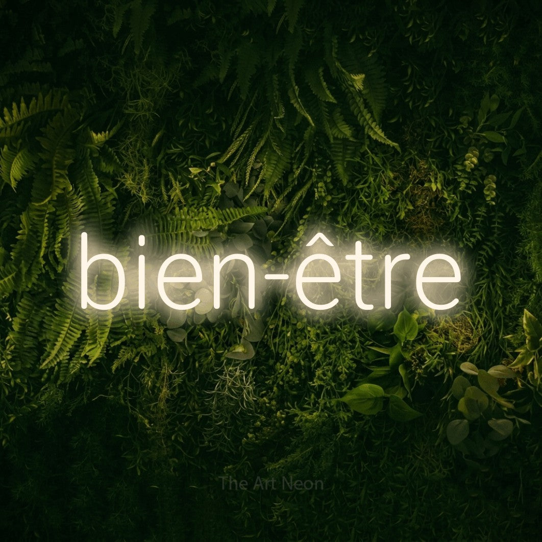 Lettrage en néon LED « Bien-être » en blanc chaud, en lettres sans empattement arrondies, présenté sur un fond sombre de mousse et de forêt, pour un salon de beauté.