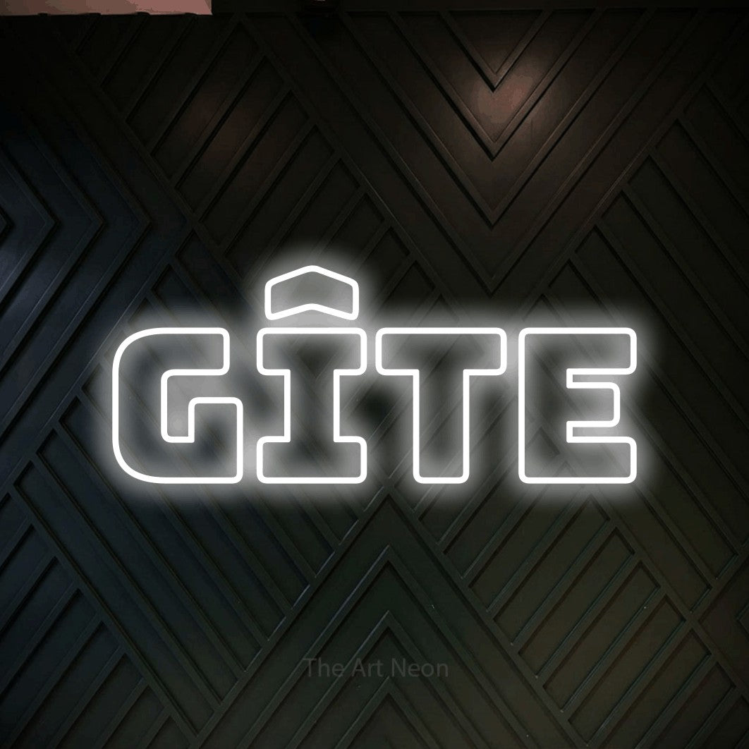 “Gîte” LED neon sign in cool white, with bold outline lettering, shown against a black chevron-patterned wood wall.