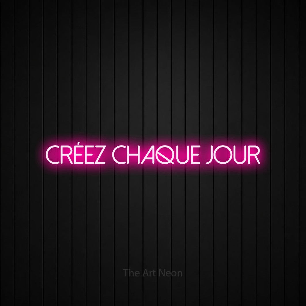 “Créez chaque jour” LED neon sign in hot pink, with thin sans-serif lettering, shown against black vertical wall slats.