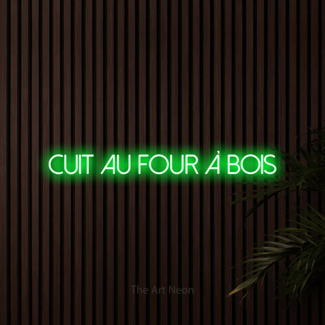 “Cuit au four à bois” LED neon sign in green, with thin sans-serif lettering, shown against dark wooden wall slats.