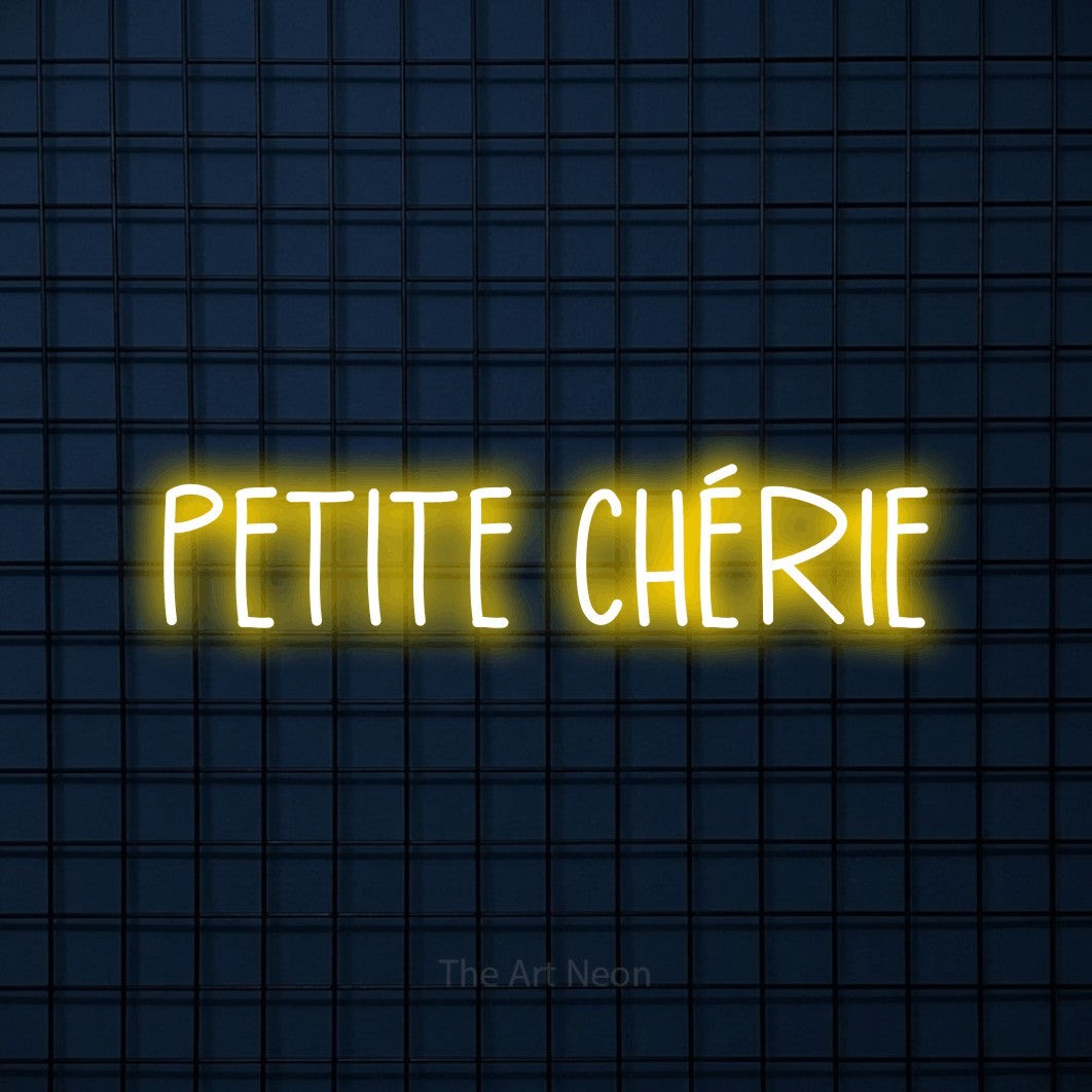 “Petite chérie” LED neon sign in yellow, with narrow hand-drawn lettering, shown against a dark blue grid.