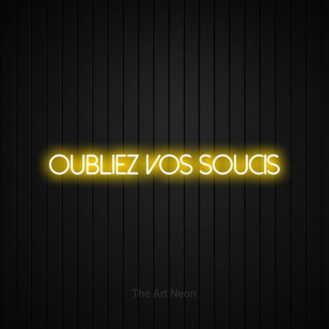 “Oubliez vos soucis” LED neon sign in yellow, with thin sans-serif lettering, shown against black vertical wall slats.
