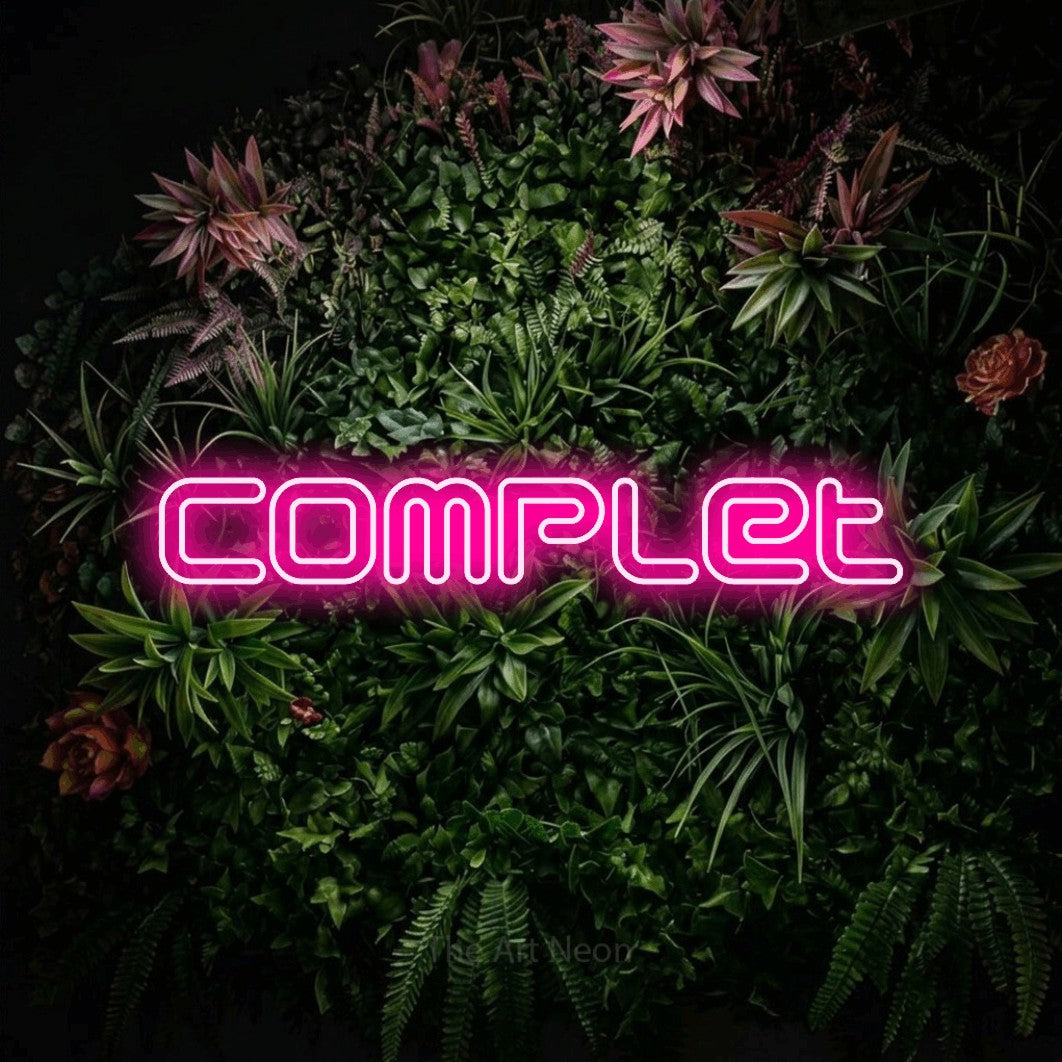 “Complet” LED neon sign in hot pink, with futuristic double-line lettering, shown against a flowering plant wall.