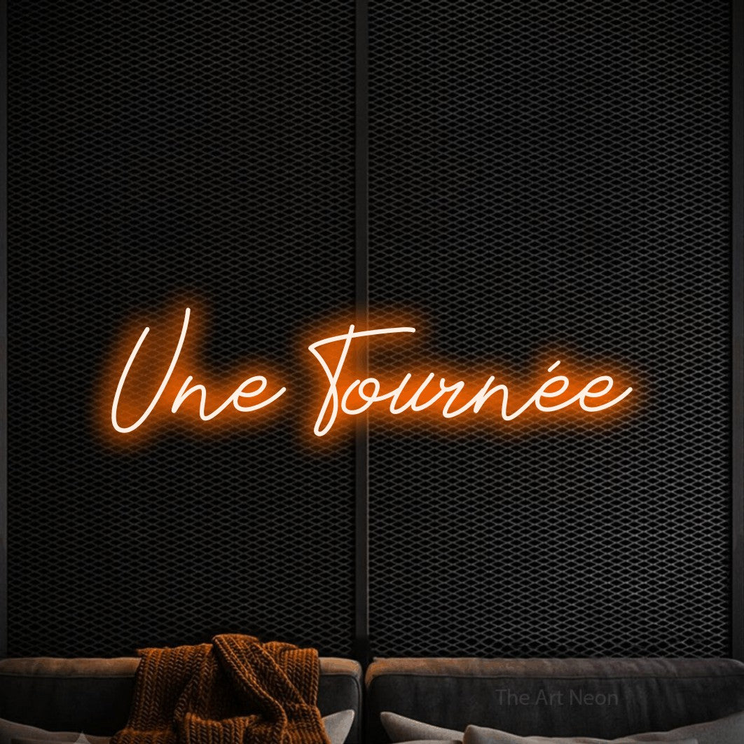 Enseigne néon LED « Une tournée » en orange, en lettrage cursif, présentée dans un coin salon moderne aux tons noirs, pour un bar à la maison.