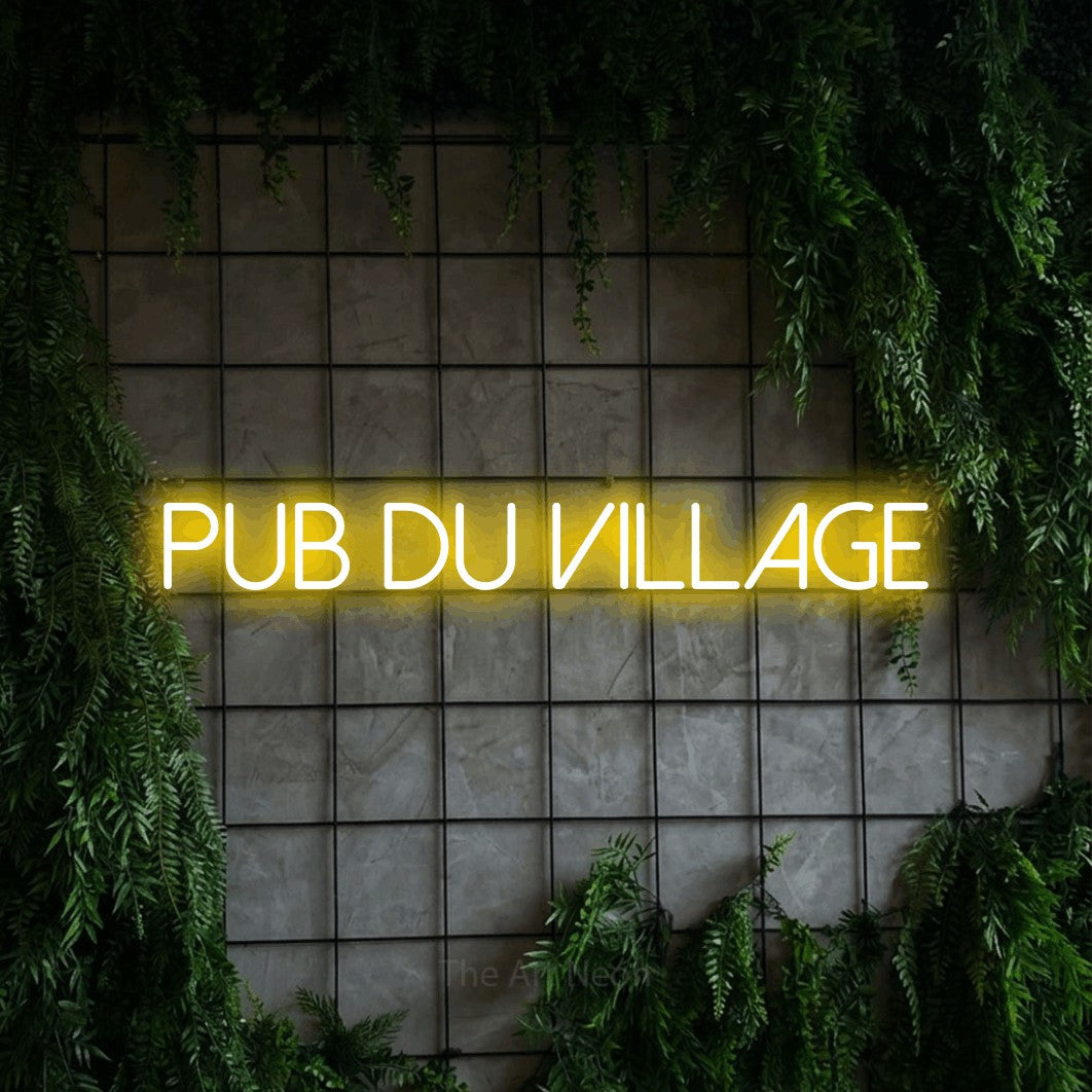 “Pub du village” LED neon sign in yellow, with thin sans-serif lettering, shown against an ivy-covered concrete grid.
