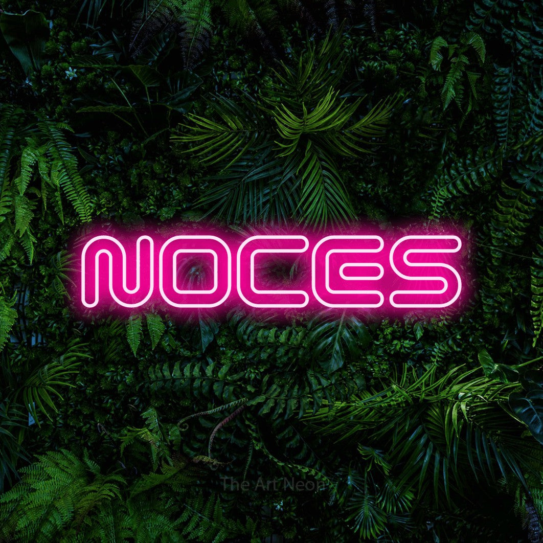 “Noces” LED neon sign in hot pink, with futuristic double-line lettering, shown against dense tropical foliage.