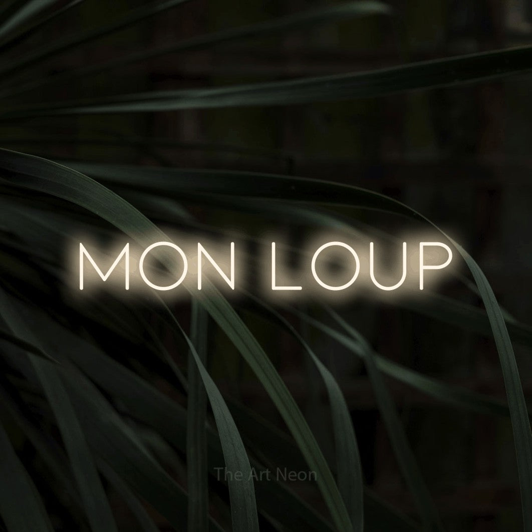 Enseigne néon LED « Mon loup » en blanc chaud, en lettres fines et espacées, présentée sur un feuillage sombre en gros plan, pour une chambre d’enfant.