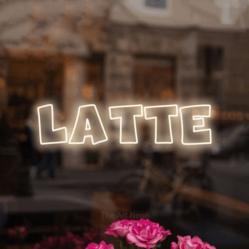 “Latte” LED neon sign in warm white, with wide lettering with irregular outlines, shown against a blurred café-bar interior.