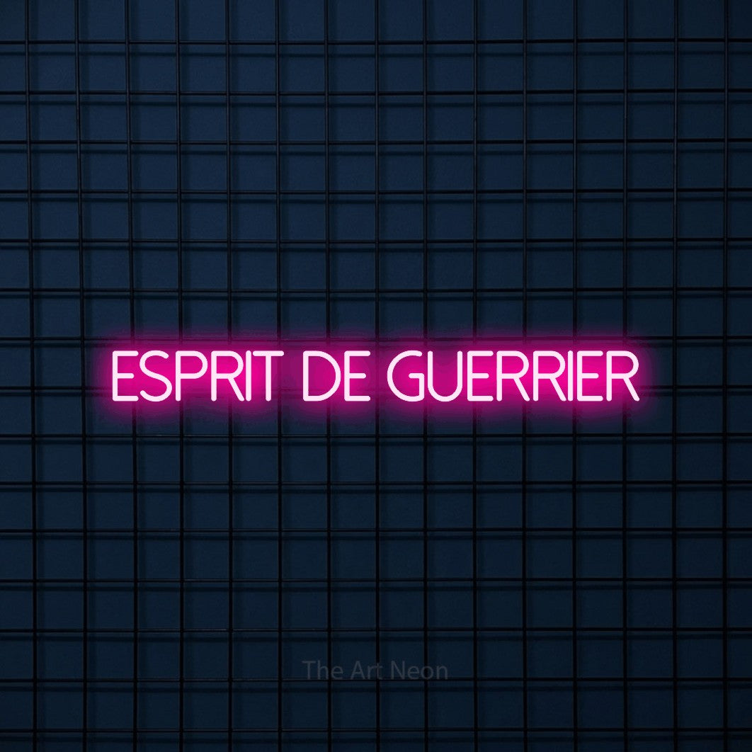 “Esprit de guerrier” LED neon sign in hot pink, with thin sans-serif lettering, shown against a dark blue grid.