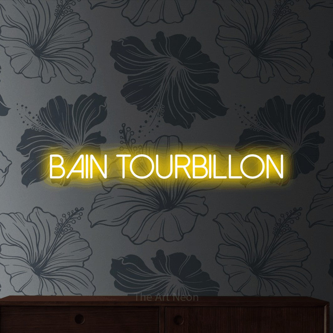 “Bain tourbillon” LED neon sign in yellow, with thin sans-serif lettering, shown against a grey floral-patterned wall.
