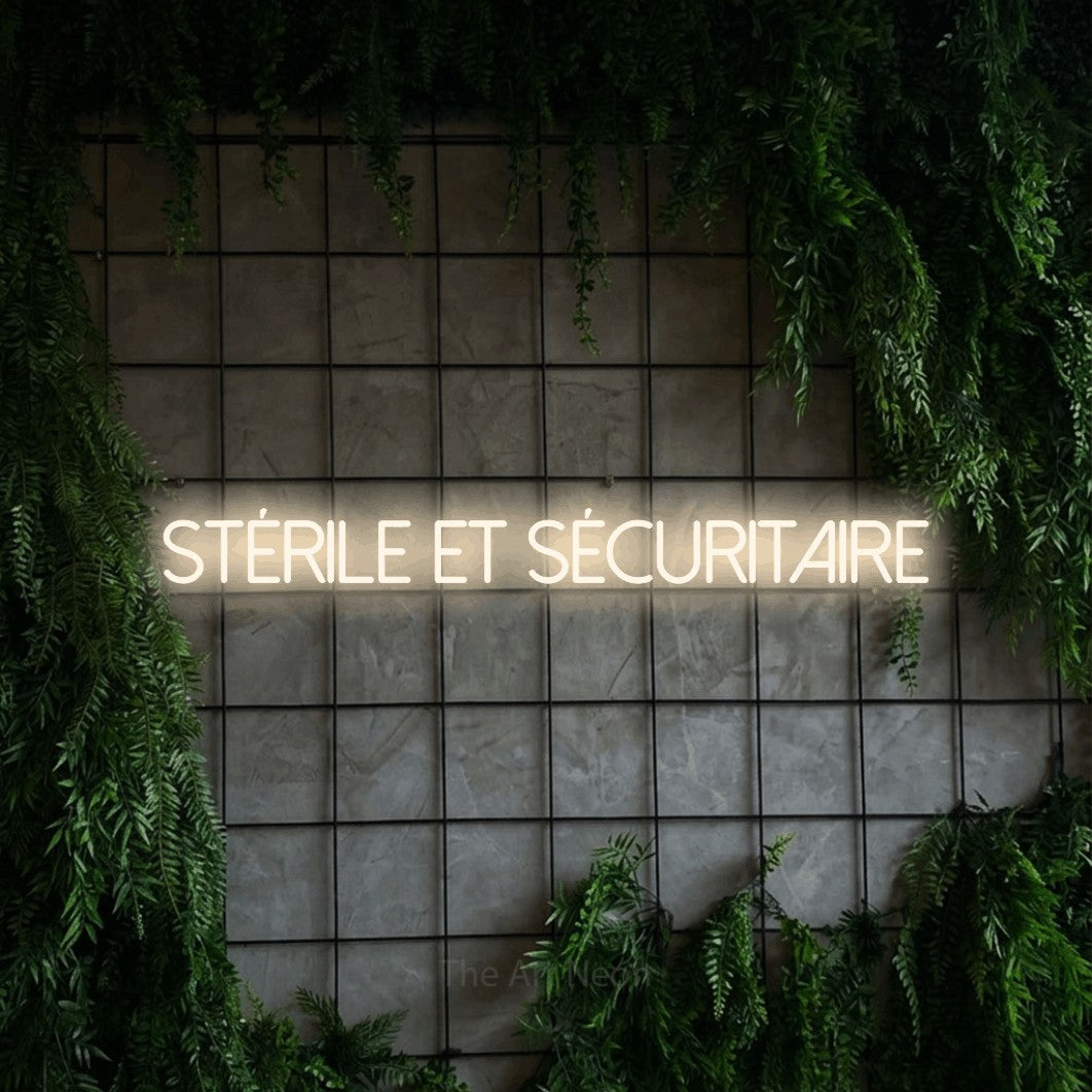 “Stérile et sécuritaire” LED neon sign in warm white, with thin sans-serif lettering, shown against an ivy-covered concrete grid.