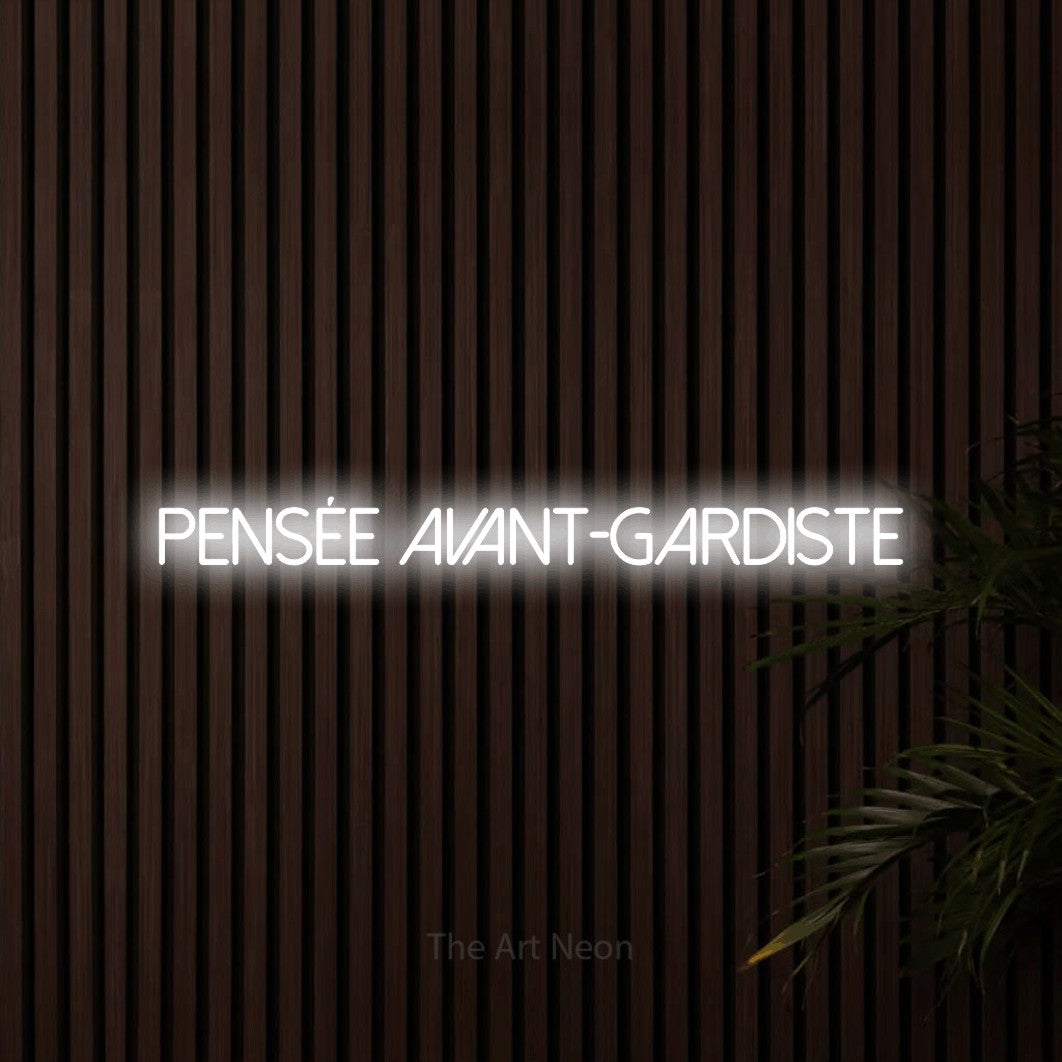 “Pensée avant-gardiste” LED neon sign in cool white, with thin sans-serif lettering, shown against dark wooden wall slats.