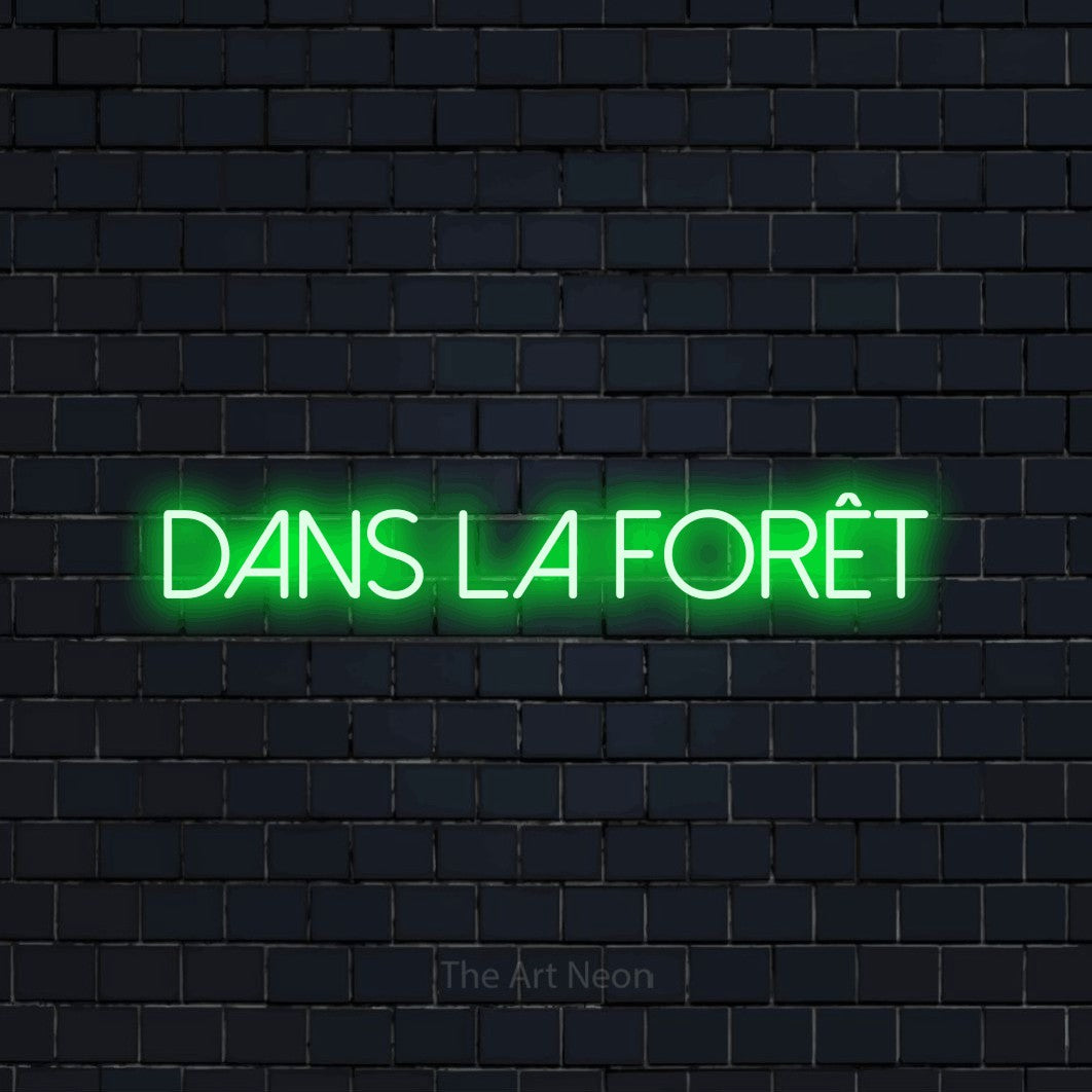 Enseigne néon LED « Dans la forêt » en vert, en lettres fines sans empattement, présentée sur un mur de briques bleu marine foncé, pour un décor inspiré de la nature.