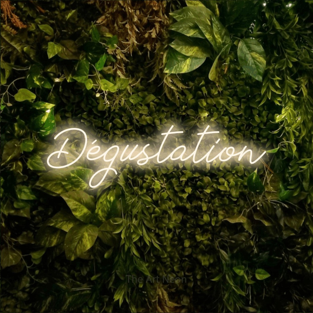 “Dégustation” LED neon sign in warm white, with cursive lettering, shown against bright green and yellow foliage.