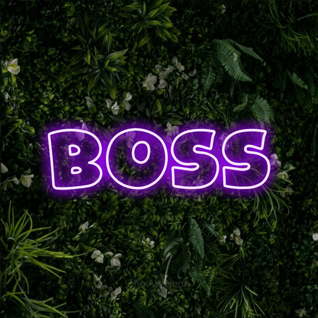 “Boss” LED neon sign in purple, with wide lettering with irregular outlines, shown against a dense green plant wall.