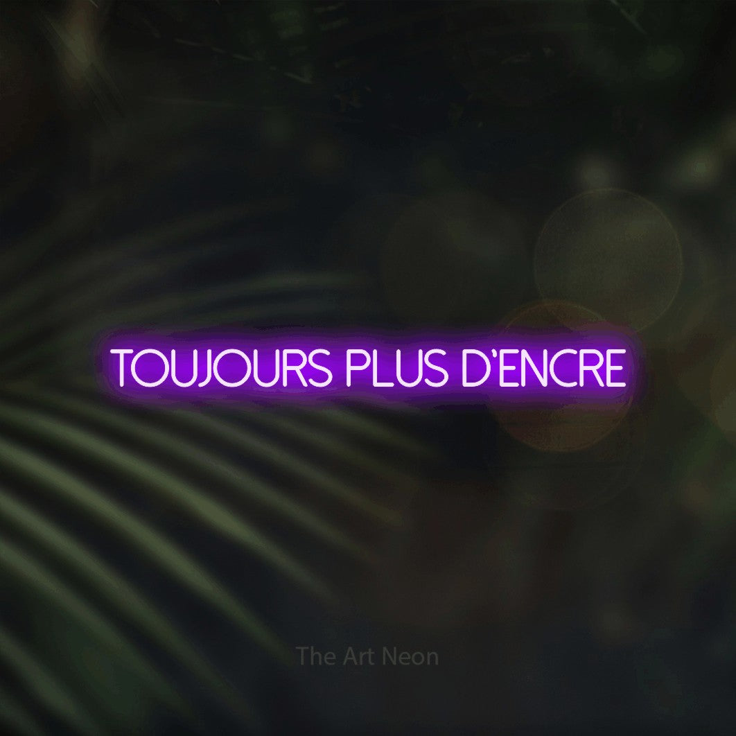 “Toujours plus d'encre” LED neon sign in purple, with thin sans-serif lettering, shown against a blurred palm and bokeh-light backdrop.