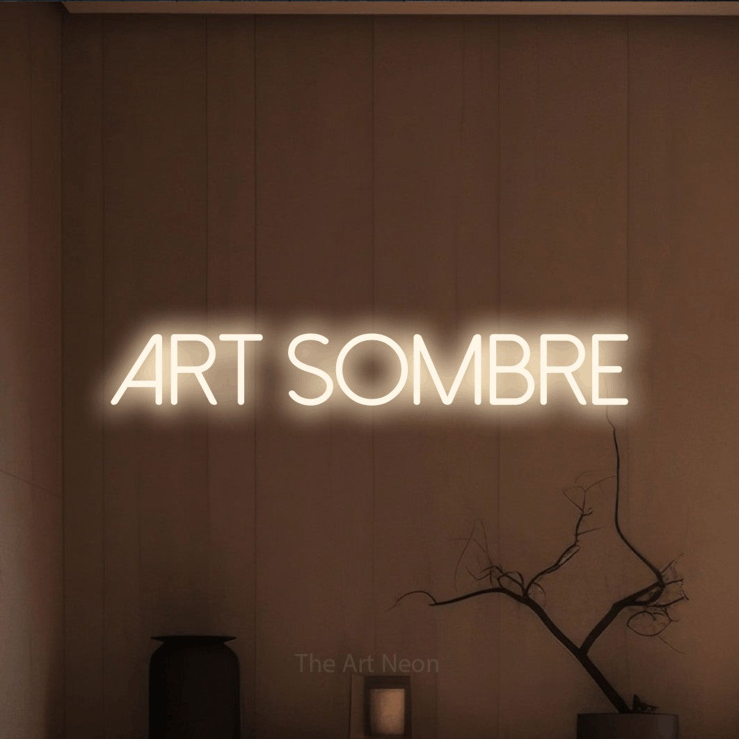 “Art sombre” LED neon sign in warm white, with thin sans-serif lettering, shown against a simple earth-toned interior.